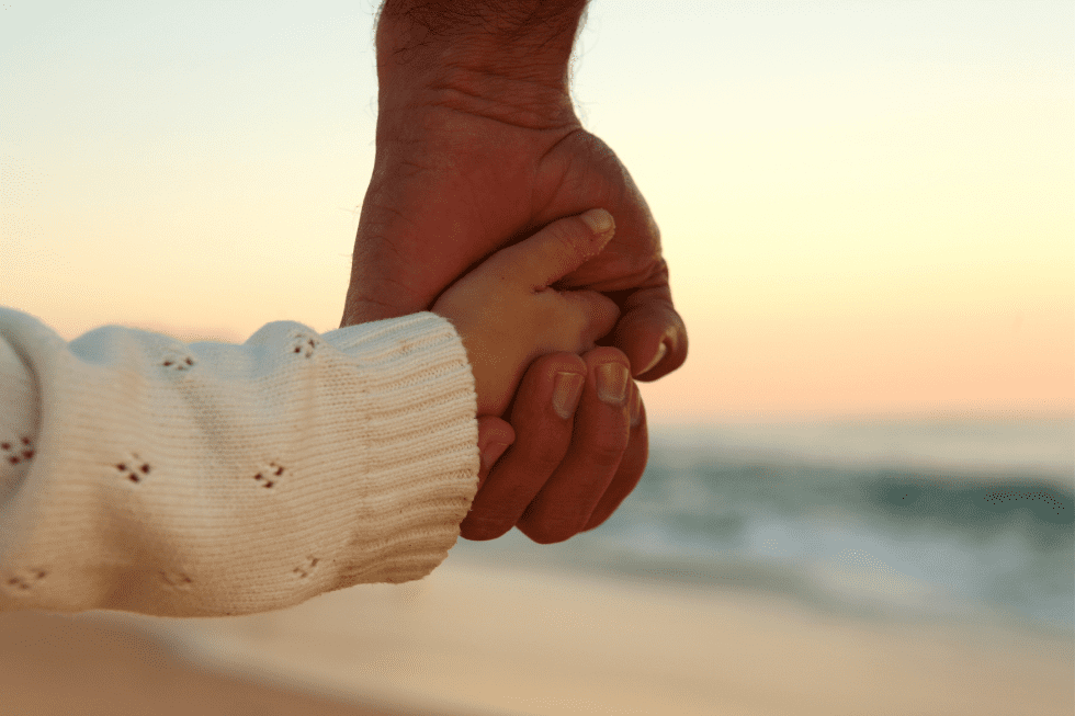 cute girl hands with her father on beach